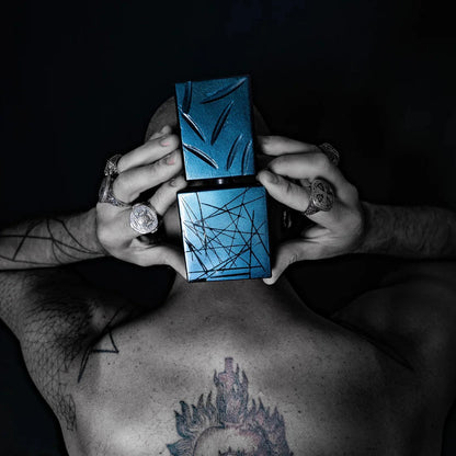 Person holding two blue square objects with intricate patterns against a dark background